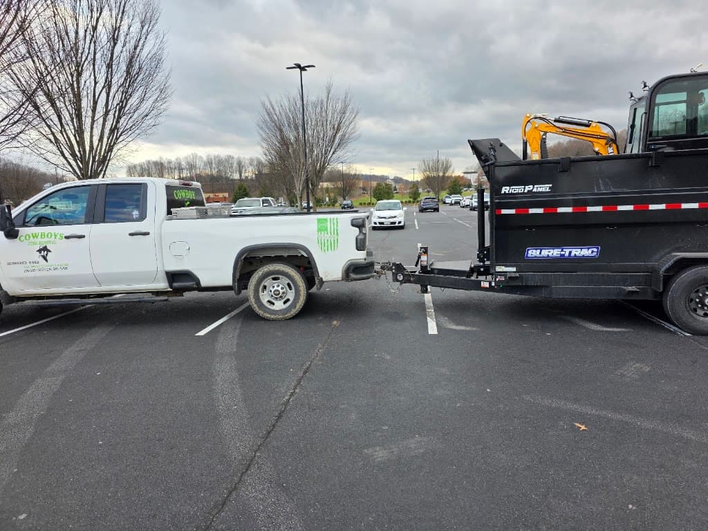 Cowboys Junk Removal truck towing a dump trailer loaded with a mini excavator